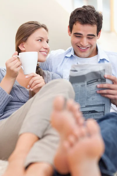Retrato de una pareja sonriente leyendo un periódico por la mañana — Foto de Stock