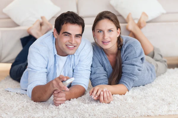 Charmant couple regardant la télévision tout en étant allongé sur un tapis — Photo