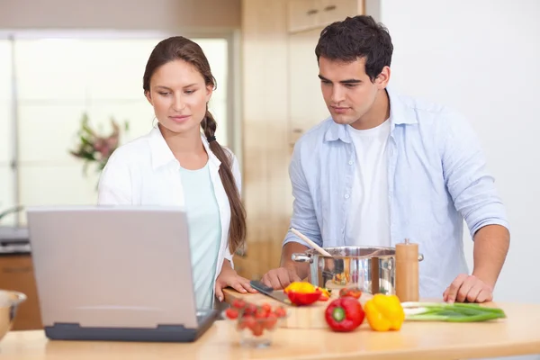 Couple using a laptop to cook — Stock Photo, Image