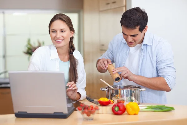 Young couple using a notebook to cook — Stock Photo, Image