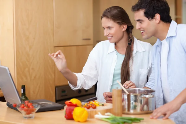 ラップトップを使用して調理するカップルの笑みを浮かべてください。 — ストック写真