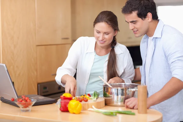 Happy couple using a laptop to cook — Stock Photo, Image