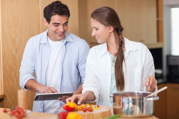Charming couple using a tablet computer to cook — Stock Photo, Image