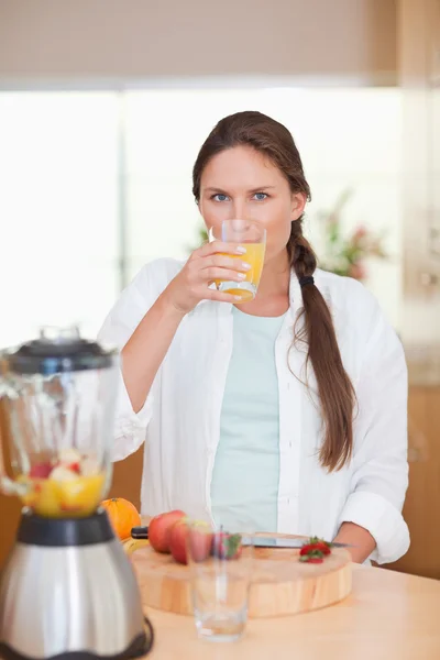 Retrato de uma mulher bonita bebendo suco de frutas frescas — Fotografia de Stock