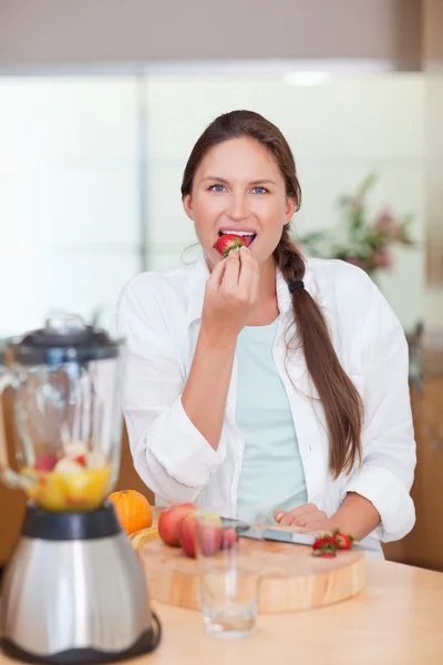 Porträt einer Frau, die eine Erdbeere isst — Stockfoto