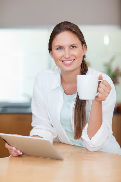 Portrait of a young woman using a tablet computer while drinking — Stock Photo, Image