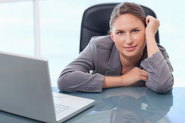 Young businesswoman leaning on her desk — Stock Photo, Image