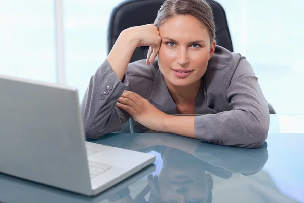 Beautiful businesswoman leaning on her desk — Stock Photo, Image