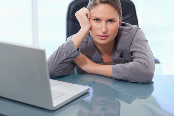 Seriös affärskvinna lutar på hennes skrivbord — Stockfoto