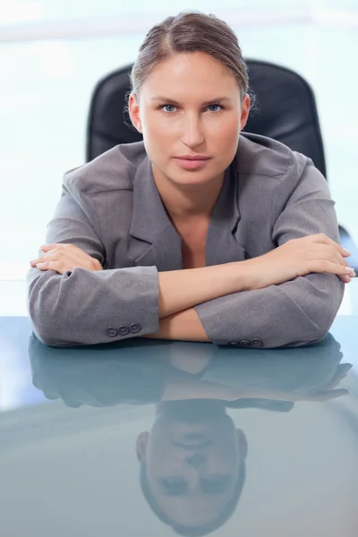 Porträt einer seriösen Geschäftsfrau, die sich auf ihren Schreibtisch lehnt — Stockfoto
