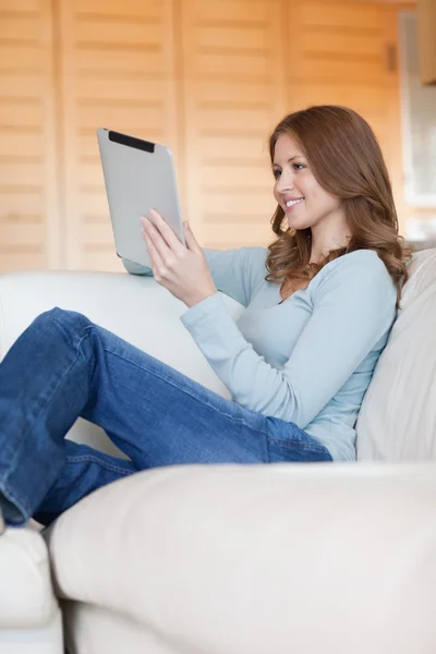 Femme souriante sur le canapé avec sa tablette — Photo