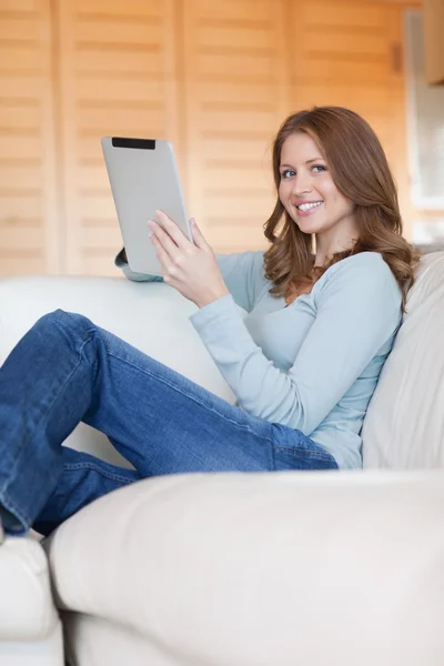 Усміхнена жінка з планшетом розслабляється на дивані — стокове фото