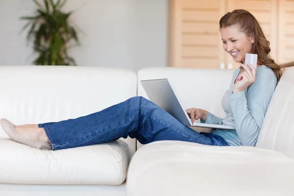 Happy woman booking flight online on the sofa — Stock Photo, Image