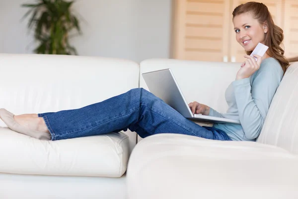 Junge Frau auf dem Sofa, die online einen Flug bucht — Stockfoto