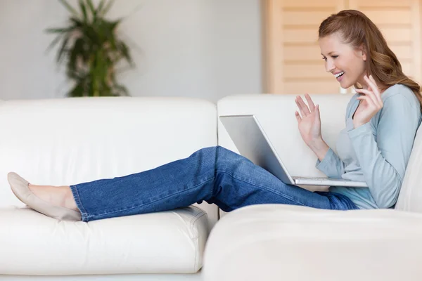 幸福微笑的女人与她的笔记本电脑在沙发上 — 图库照片