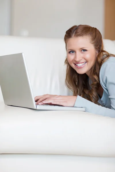 Счастливая женщина на диване с ноутбуком — стоковое фото