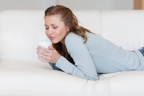 Mujer joven disfrutando de una pausa para tomar café en el sofá — Foto de Stock