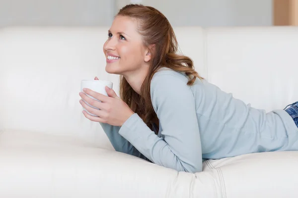 Genç kadın zevk onun kanepede kahve molası — Stok fotoğraf