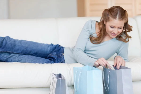 Feminino no sofá olhando em sacos de compras — Fotografia de Stock