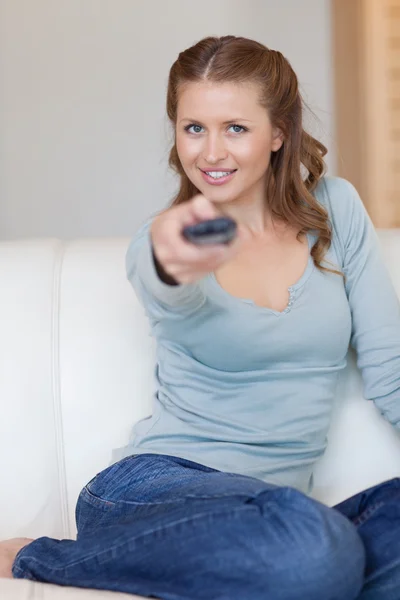 Young woman on the sofa switching on tv — Stock Photo, Image