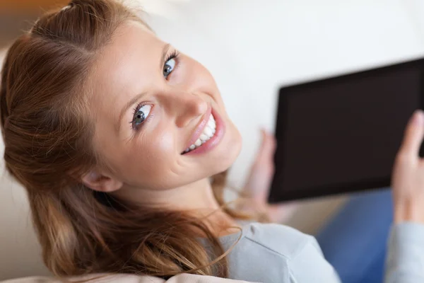 Shadowing smiling woman on the sofa with tablet — Stock Photo, Image