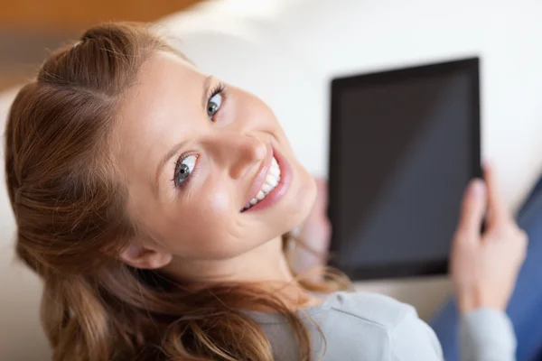 在沙发上微笑着女人与平板电脑的视图上方 — 图库照片