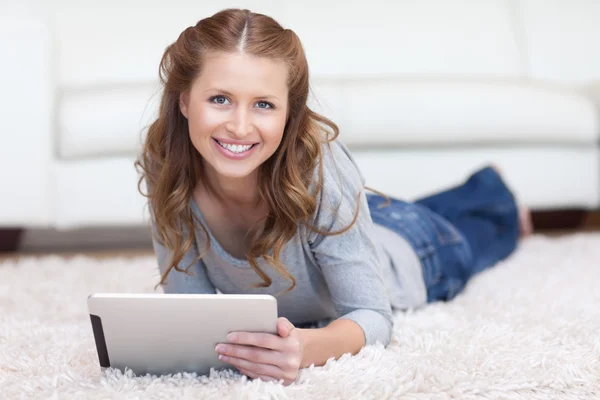 微笑的女士在地板上使用她的平板电脑 — 图库照片