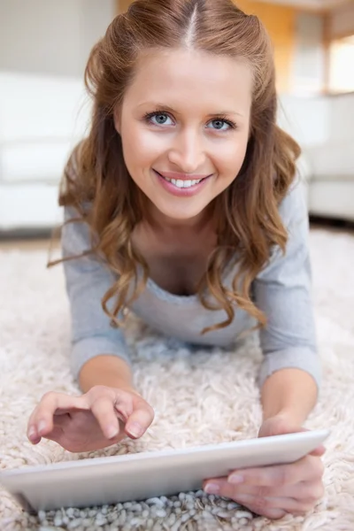Усміхнена жінка на підлозі зі своїм планшетом — стокове фото