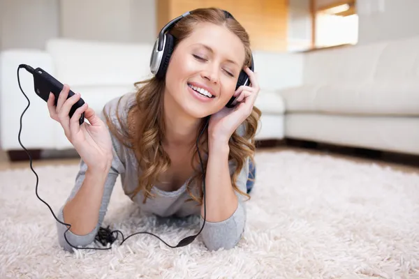 Frau liegt auf dem Teppich und genießt Musik — Stockfoto