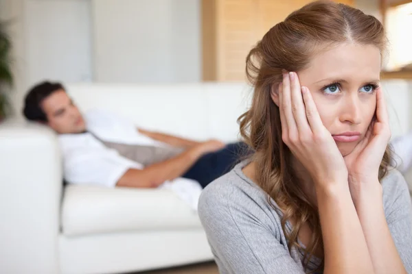 Mujer triste mirando con el hombre en el sofá detrás de ella —  Fotos de Stock