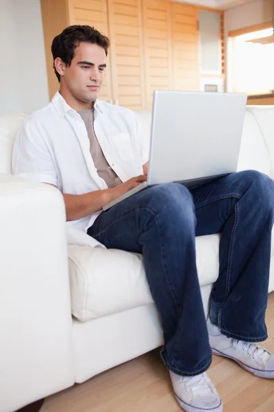 Hane med laptop i soffan — Stockfoto