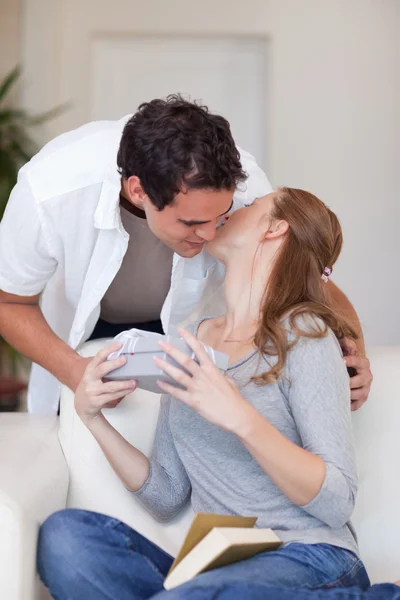 Женщина целует своего парня в знак благодарности за подарок — стоковое фото
