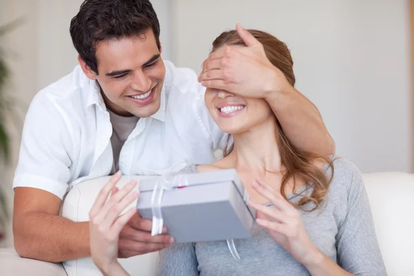 Man covering the eyes of his girlfriend while giving her a prese — Stock Photo, Image