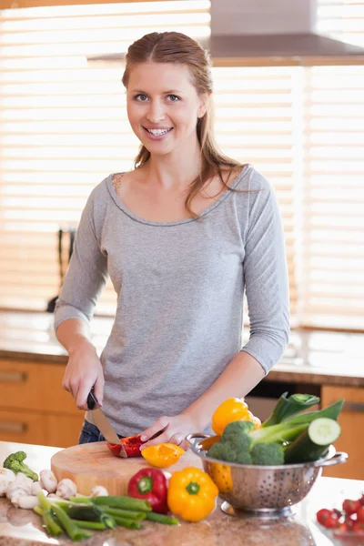 Femme souriante coupe ingrédients pour la salade — Photo