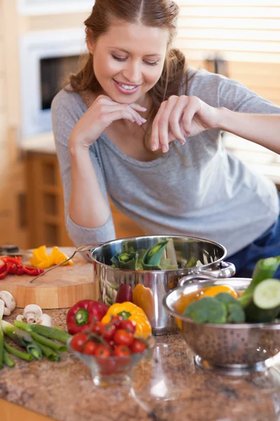Mulher aromatizando os ingredientes de sua refeição — Fotografia de Stock
