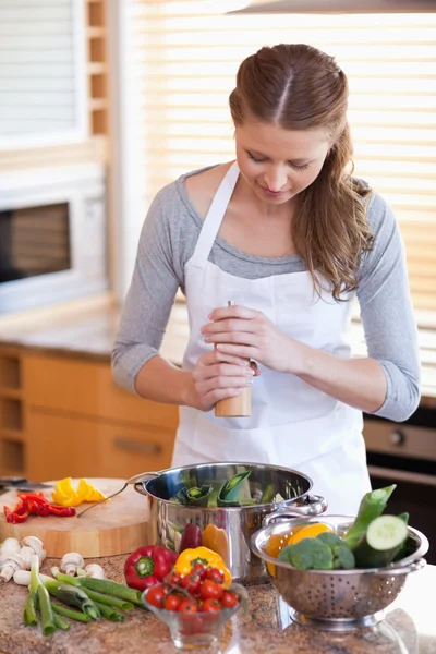Woman peppering her meal — Stock Photo, Image