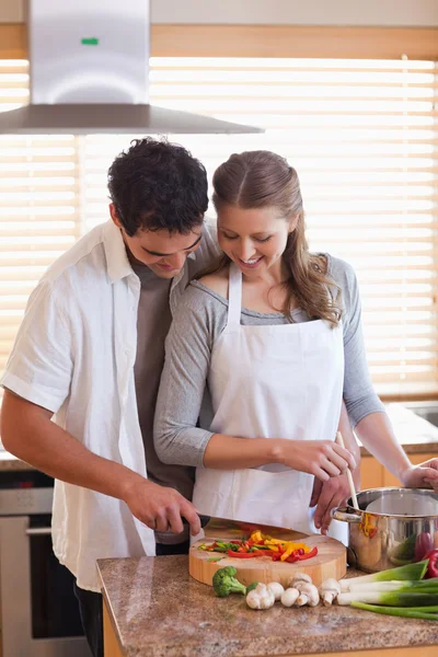Homem cortando ingredientes para ajudar sua namorada — Fotografia de Stock