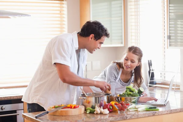 Couple using laptop to look up recipe for their meal — Stock Photo, Image
