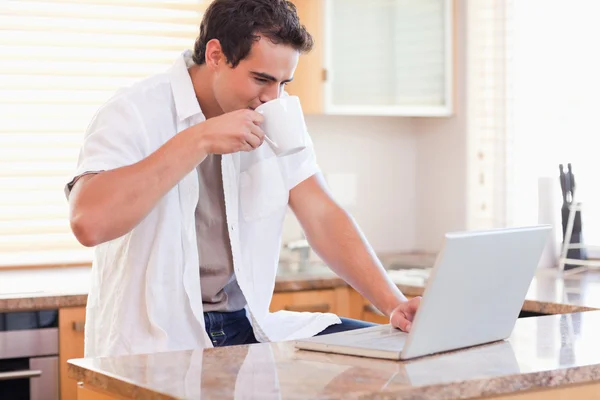 Adam kitc onun laptop üzerinde çalışırken kahve içme — Stok fotoğraf