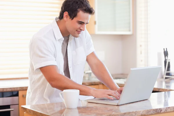 Man aan het werk op zijn laptop in de keuken — Stockfoto