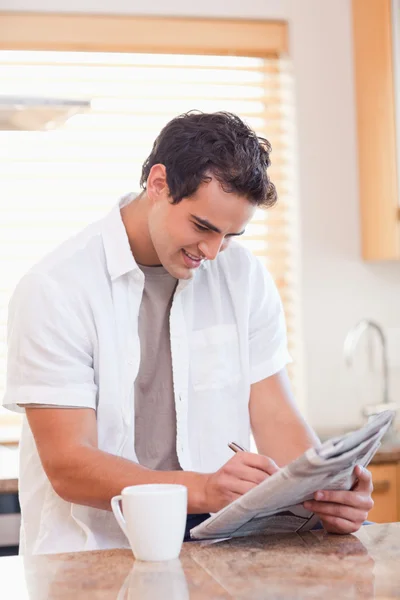 Man solving crossword puzzle in the kitchen — Stock Photo, Image