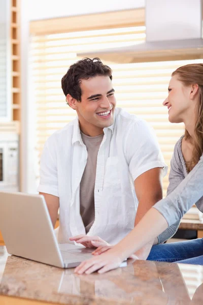 Smiling couple with laptop in the kitchen — Stock Photo, Image