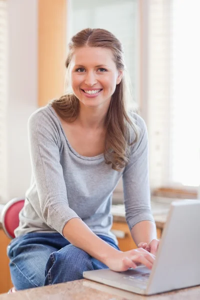 Mulher digitando em seu laptop na cozinha — Fotografia de Stock