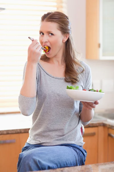 Kobieta jedząc sałatkę w kuchni — Zdjęcie stockowe
