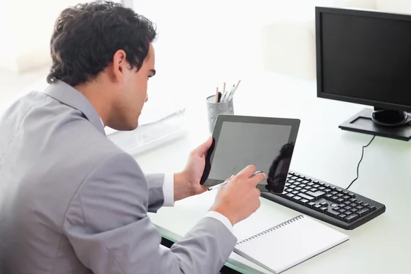 Empresário olhando para seu tablet em seu escritório — Fotografia de Stock