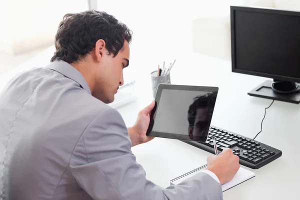 Empresário copiando de seu tablet em seu calandra bolso — Fotografia de Stock