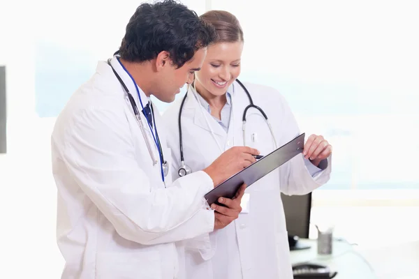 Assistant doctors reading off clip board — Stock Photo, Image