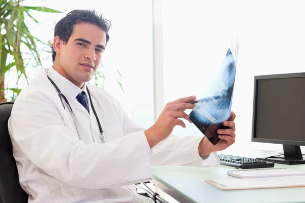 Vista lateral do médico sentado em seu escritório com um raio-x — Fotografia de Stock