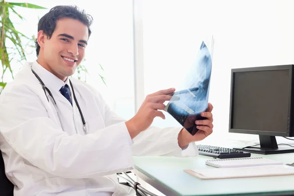 Vista lateral do jovem médico em sua mesa com um raio-x — Fotografia de Stock