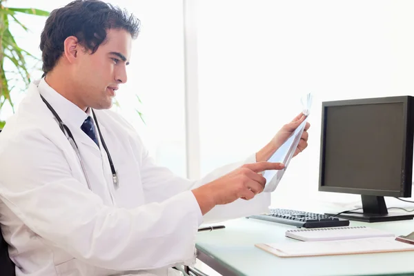 Vista laterale del medico con una radiografia alla scrivania — Foto Stock